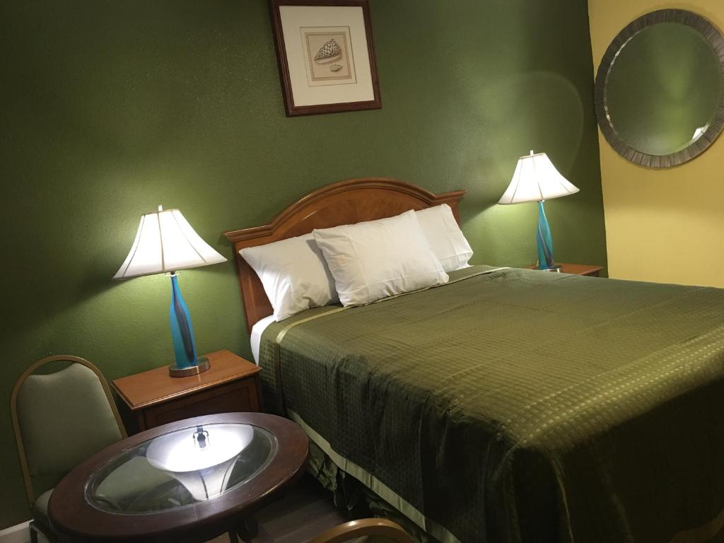 Habitación de hotel con cama, mesa y lámparas en Aristocrat Motel, en Baldwin Park