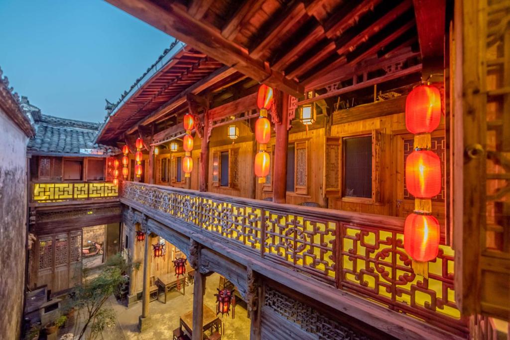 un balcón de un edificio antiguo con faroles rojos en Huangshan Xidi Shang De Tang, en Yi