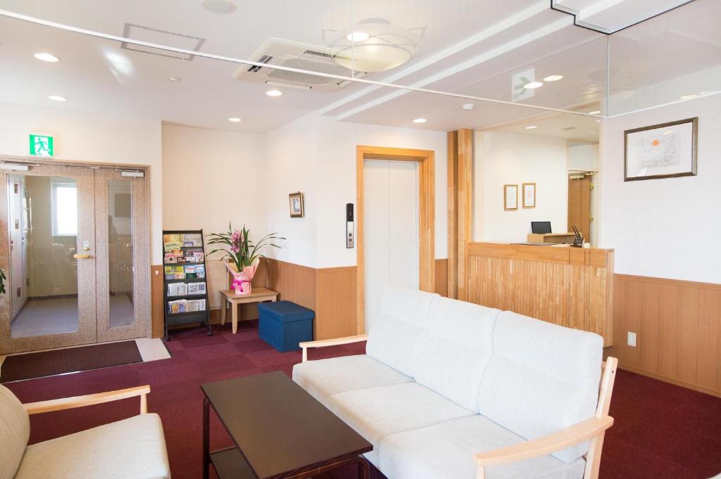 una sala d'attesa con un divano bianco e un tavolo di Hotel All In Stay Hakodate a Hakodate