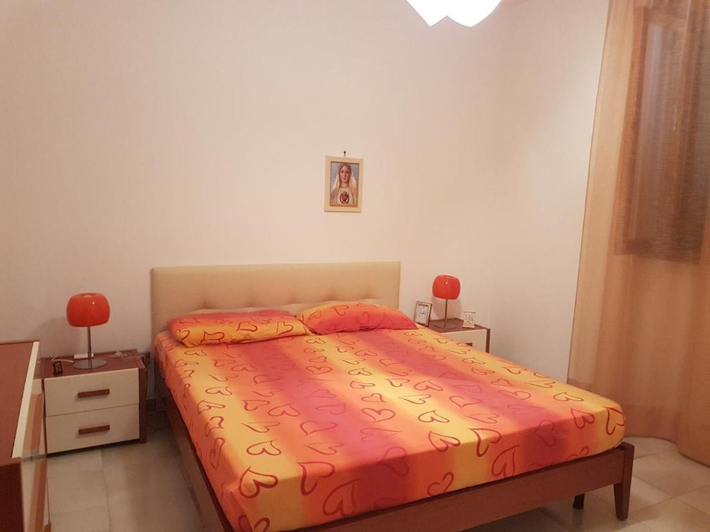 ポルト・チェザーレオにあるCasa vacanza Andreaのベッドルーム1室(オレンジのシーツとランプ2つ付)