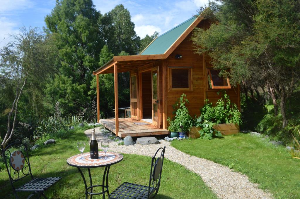 a wooden cabin with a table and chairs in the yard at First Light Rangihaeata Retreat in Takaka