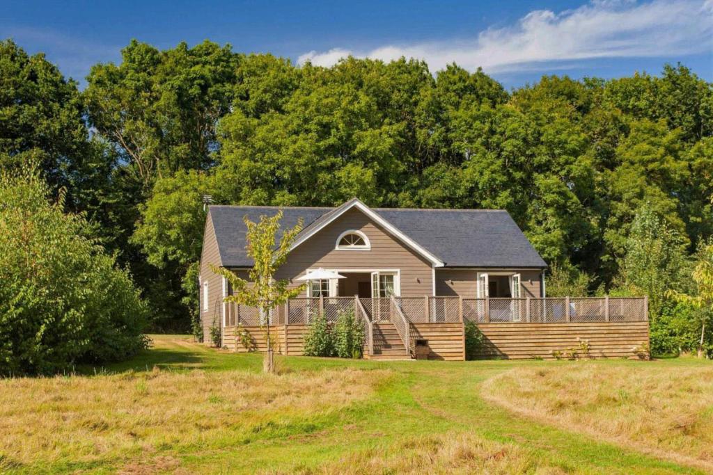 a house in a field with trees in the background at Campion Lodge in Chappel