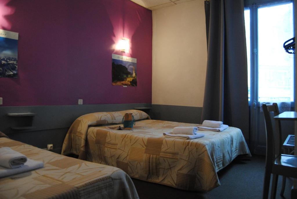 a hotel room with two beds and a window at Hôtel de Genève in Lourdes