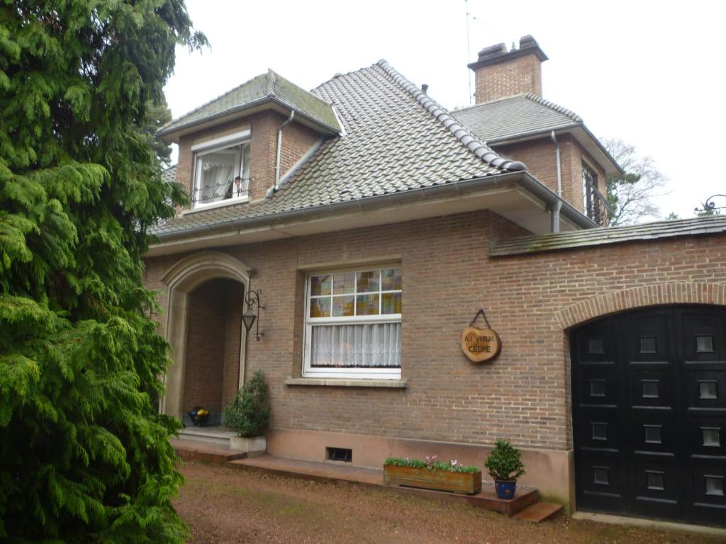 a brown brick house with a black garage at au vieux cèdre in Mouvaux