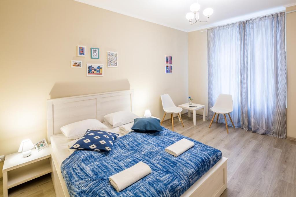 リヴィウにあるDominic Apartmentsのベッドルーム1室(大型ベッド1台、青いシーツ、白い枕付)