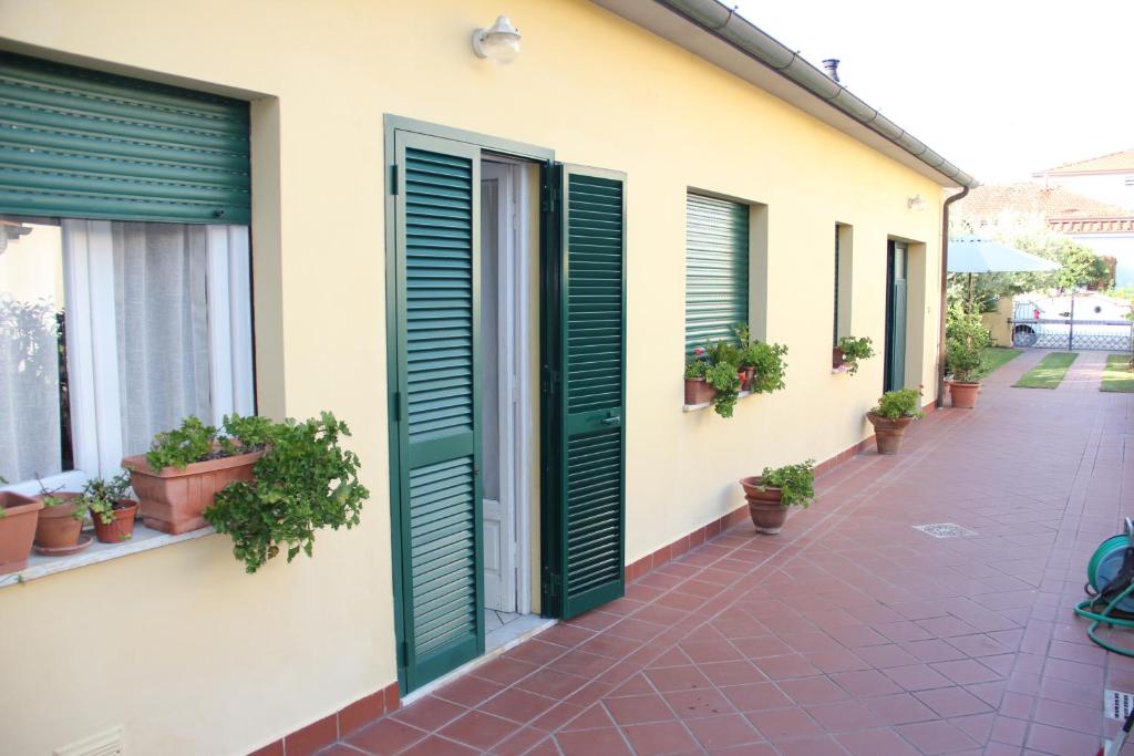 a building with green shutters and potted plants at La casina dell'Annetta in Lido di Camaiore
