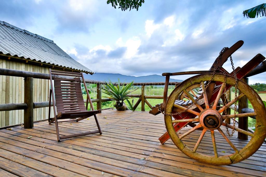 una terraza de madera con una rueda de madera y una silla en Pousada Vó Liane, en Praia Grande