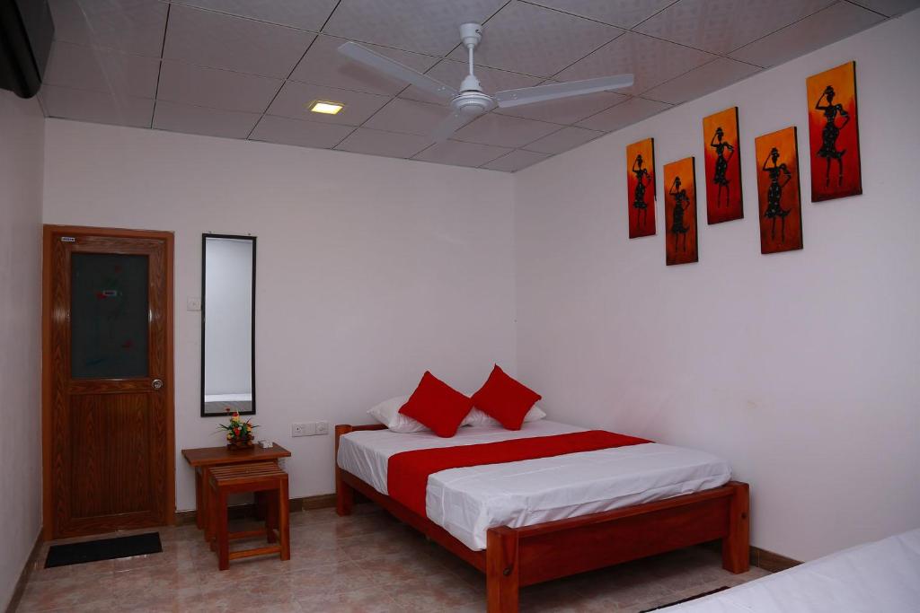 - une chambre avec un lit doté d'oreillers rouges dans l'établissement Wild Breeze, à Tissamaharama