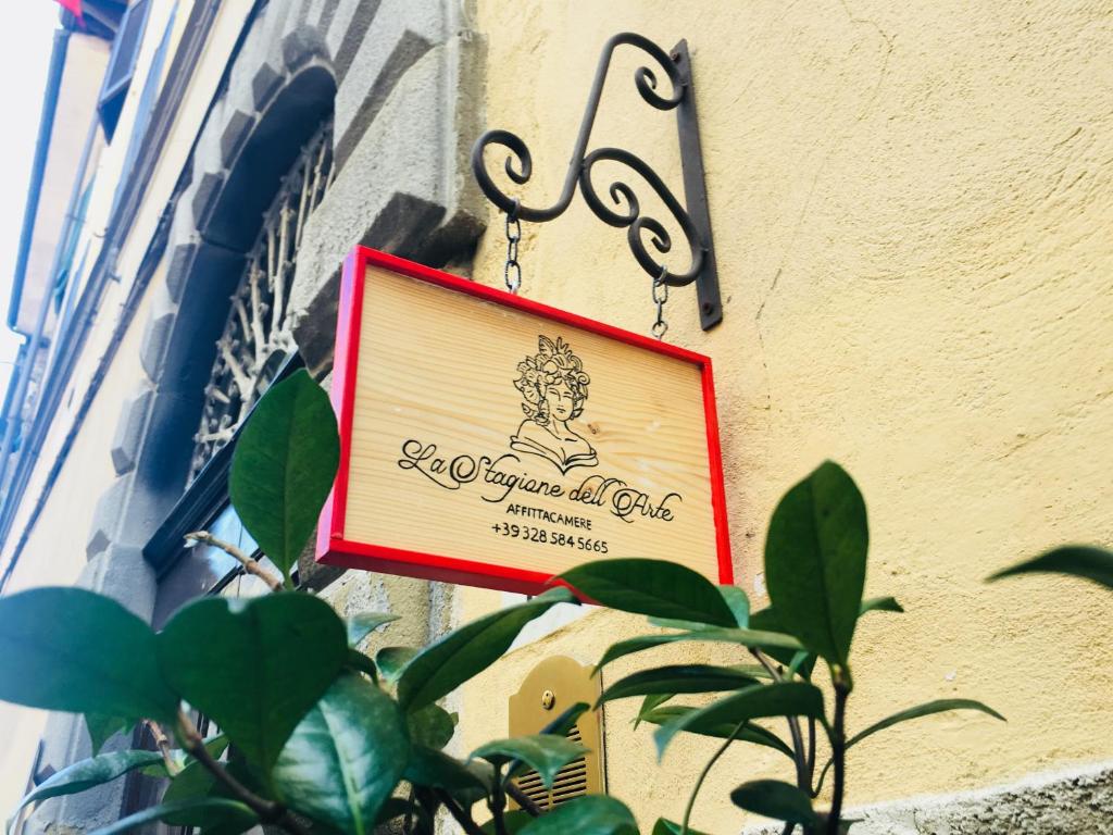 a sign on the side of a building with a plant at La Stagione dell'Arte in Camaiore