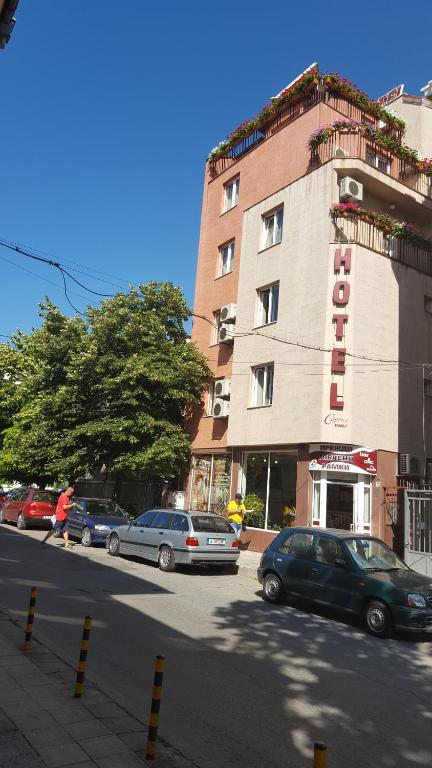 a building with cars parked on the side of a street at Caprice Family Hotel in Varna City