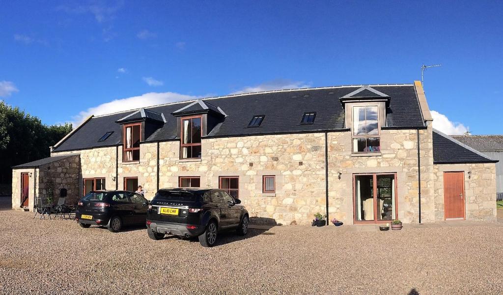 a large stone house with two cars parked in front of it at Forest View in Fraserburgh