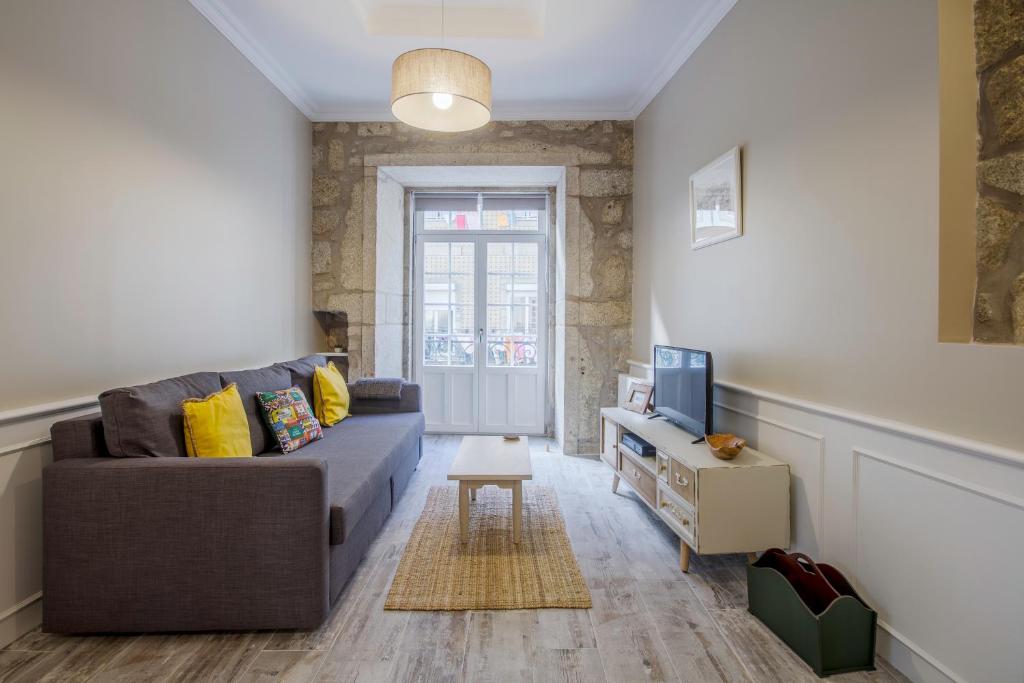 ein Wohnzimmer mit einem Sofa und einem TV in der Unterkunft OHH -S João apartments- Riverside in Porto