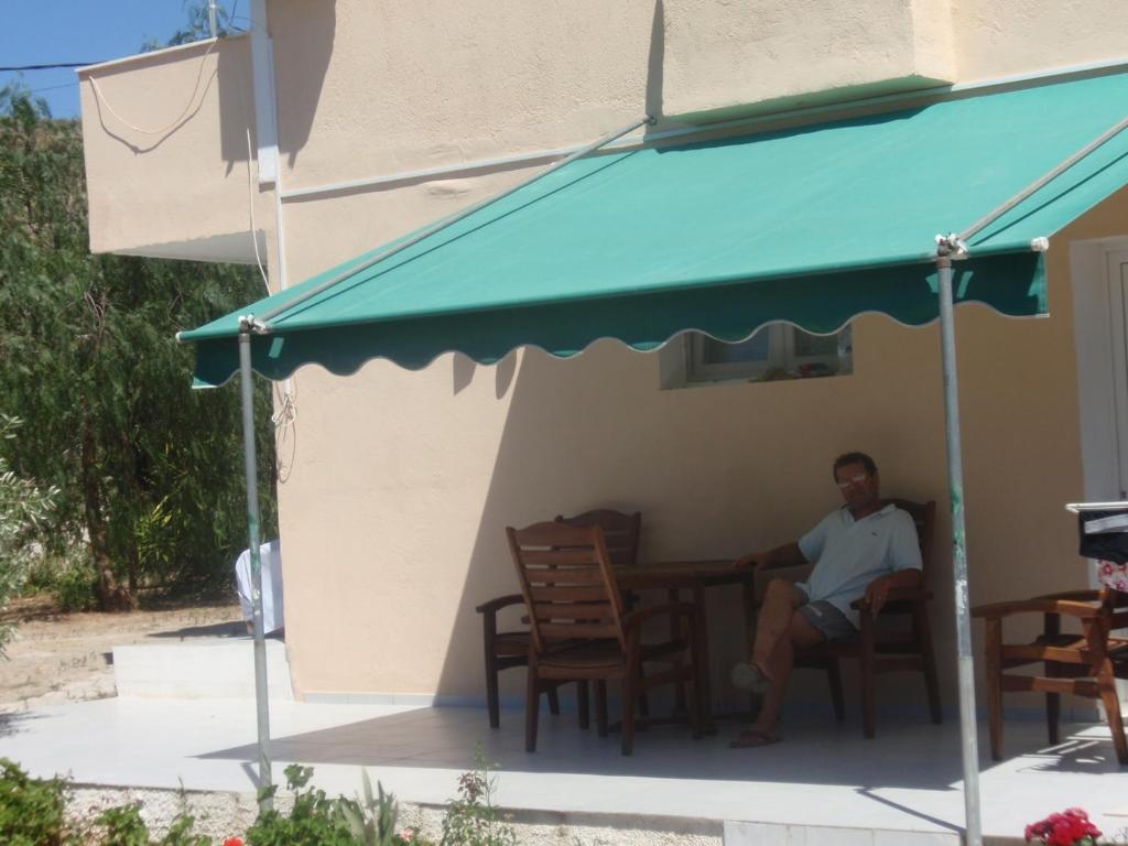 een man aan een tafel onder een paraplu bij Apartment in Lagonisi in Lagonissi