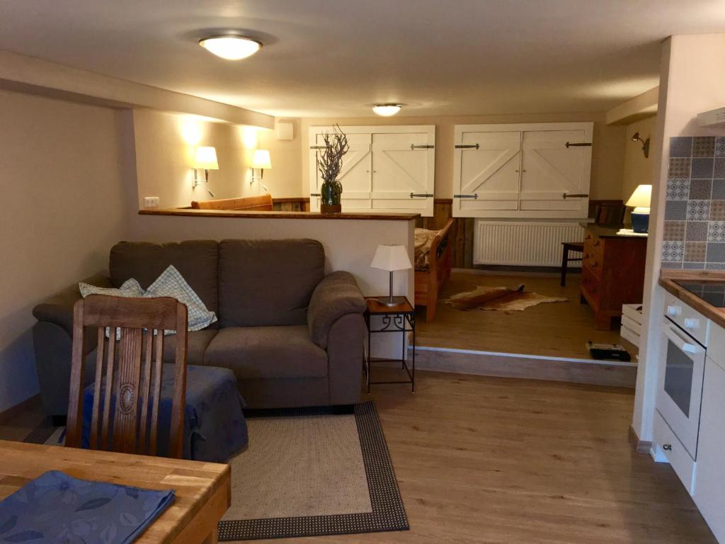 ein Wohnzimmer mit einem Sofa und einer Küche in der Unterkunft Apartment,Wohnung & Zimmer 'Am Waldfreibad' in Much
