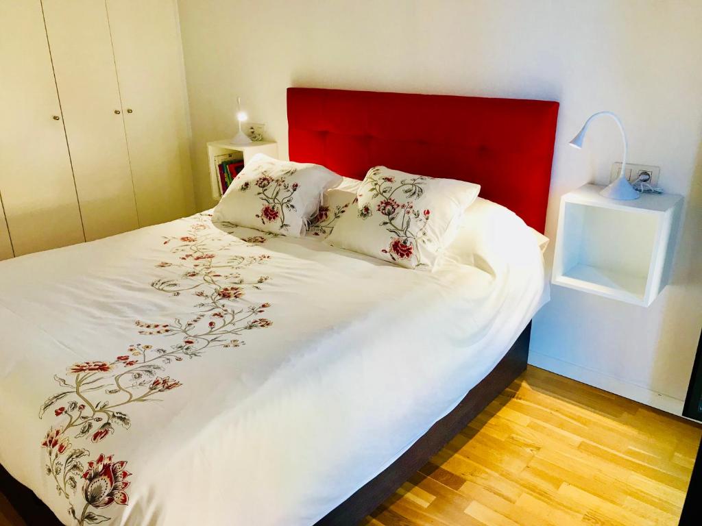 1 cama con cabecero rojo y sábanas y almohadas blancas en La casita de Palomar - PalomarGroup, en Valencia