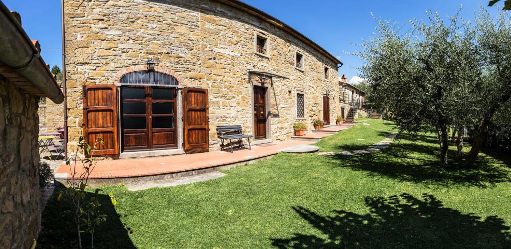 a stone building with a wooden door and a grass yard at Agriturismo Borgo tra gli Olivi in Castiglion Fiorentino
