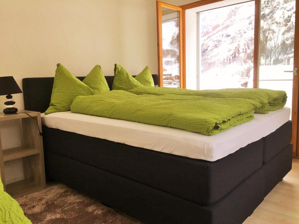 a large bed with green pillows on top of it at Apartments Soldanella in Leukerbad