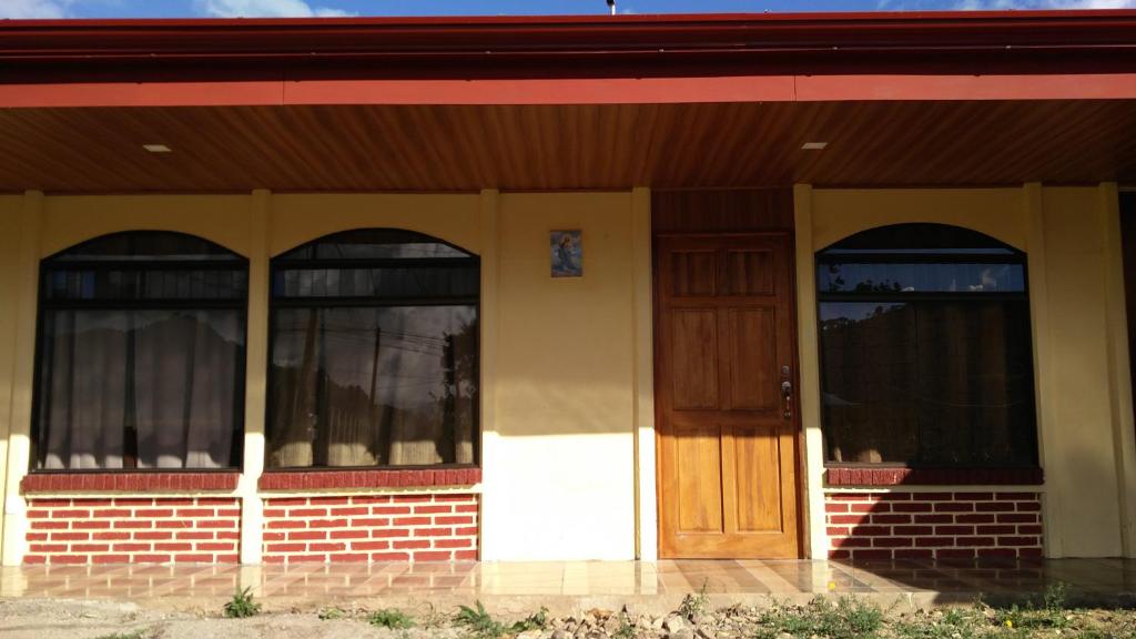 ein Haus mit drei Fenstern und einer Holztür in der Unterkunft Casa en zona tranquila y rural in Higueronal