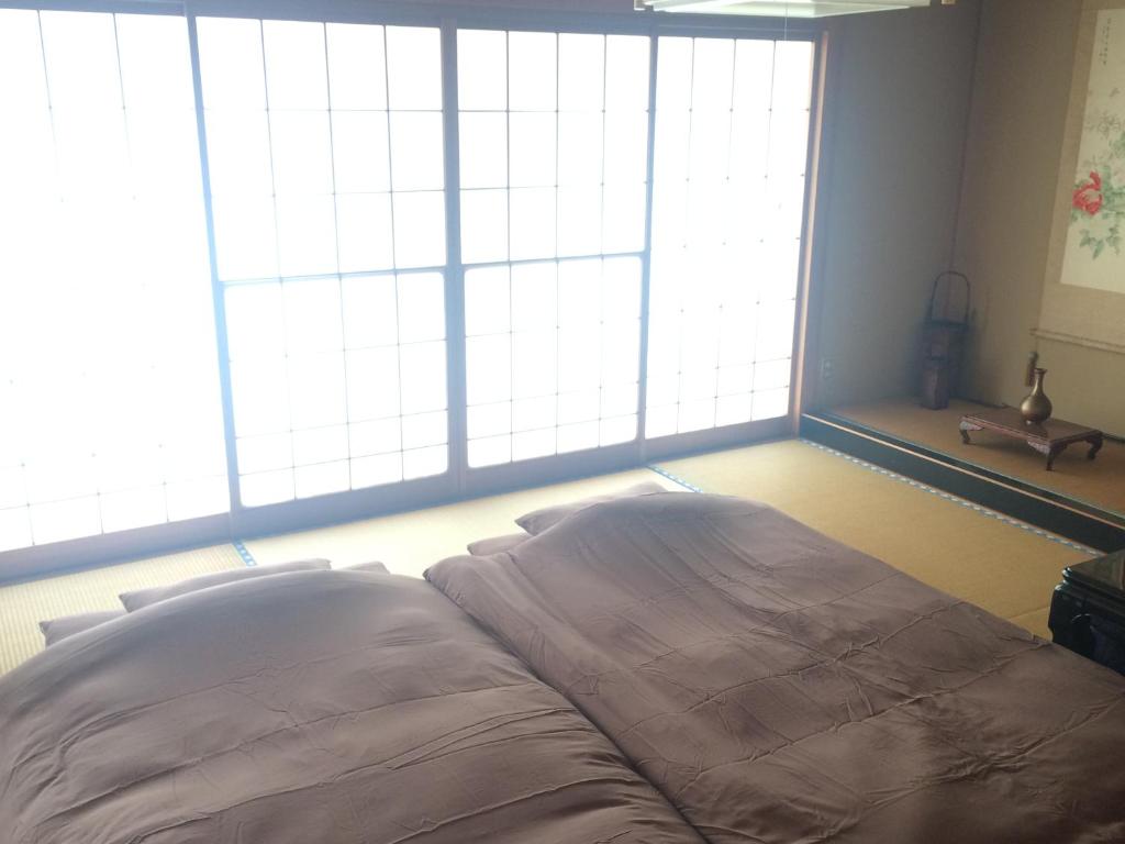 松本市にあるEN Guest houseの大きな窓2つが備わるドミトリールームのベッド1台分です。