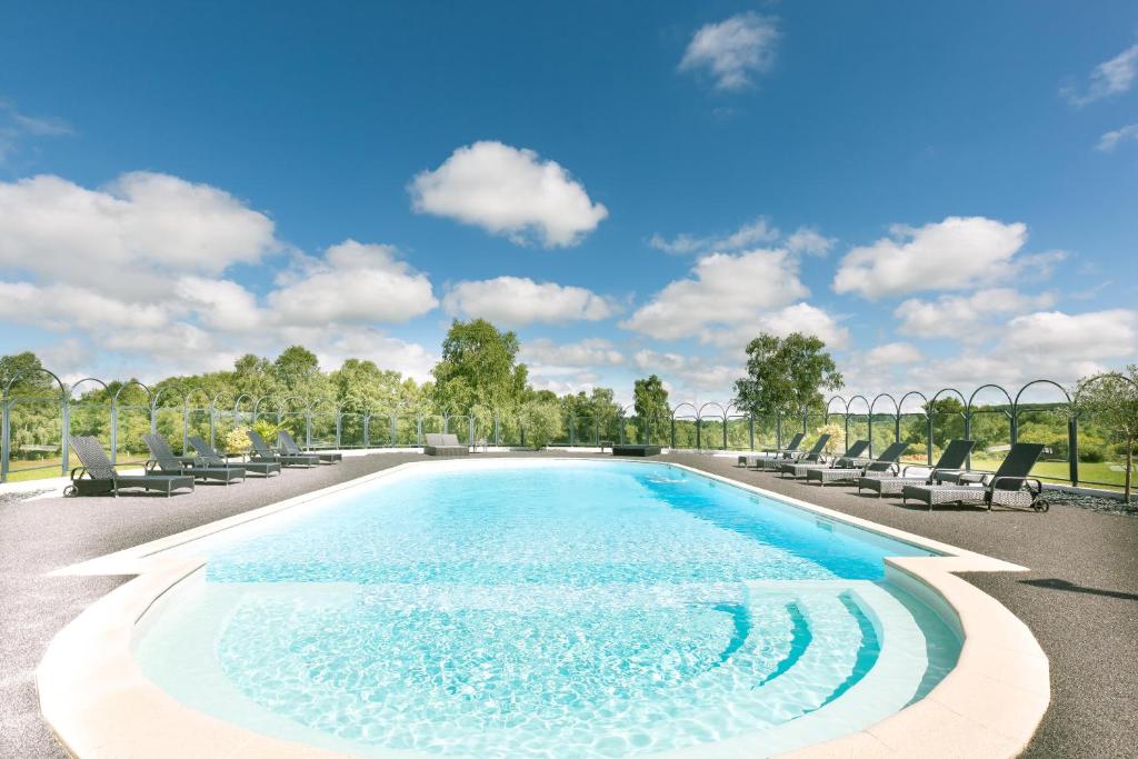 einen Pool mit Liegestühlen und blauem Himmel in der Unterkunft Hôtel du Casino de Capvern in Capvern