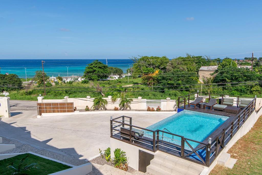 a swimming pool with chairs and the ocean in the background at Luxury 2BR Home facing Beach w/Pool Montego Bay #5 in Montego Bay