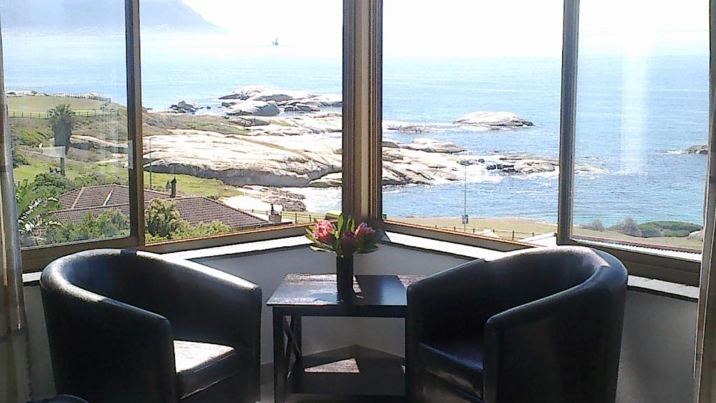 a room with two chairs and a table with a view of the ocean at Dream a Little in Simonʼs Town