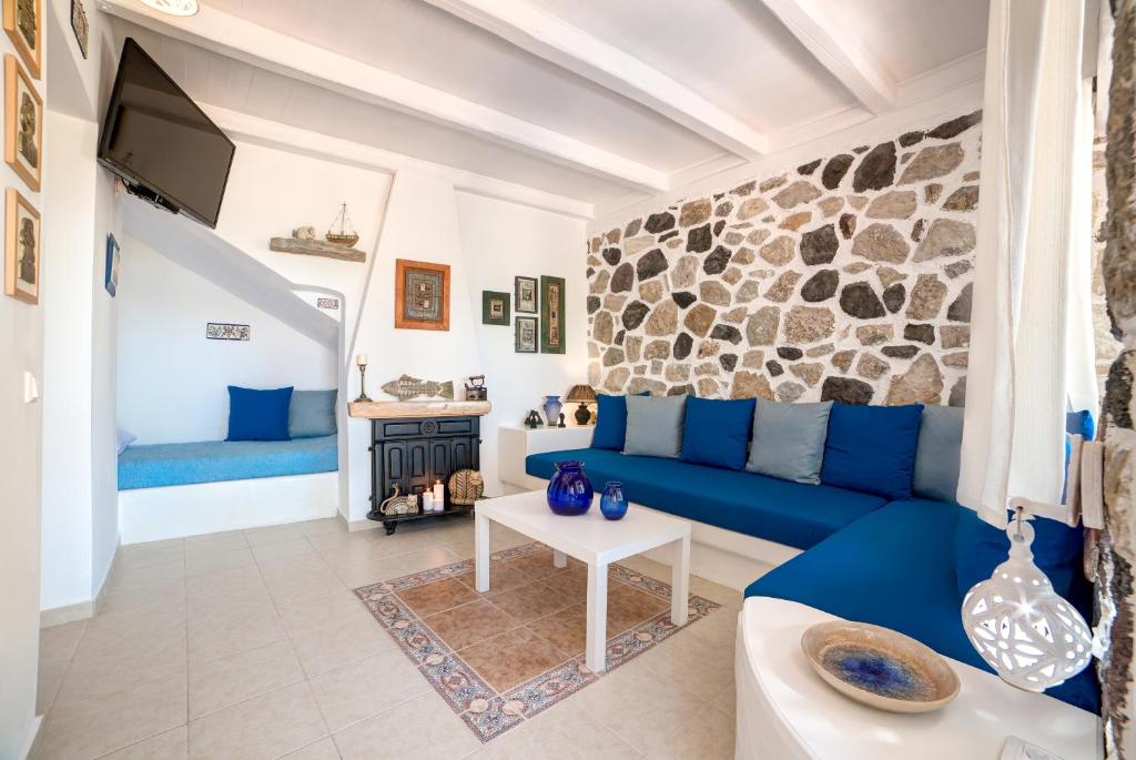 un soggiorno con divano blu e parete in pietra di Moschatos Beach House a Kamari