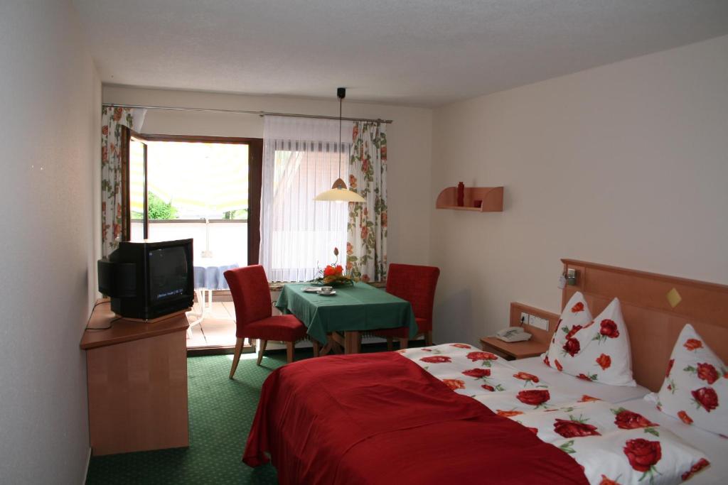 Habitación de hotel con cama, mesa y TV en Lug ins Land Restaurant & Ferienwohnungen en Bad Bellingen