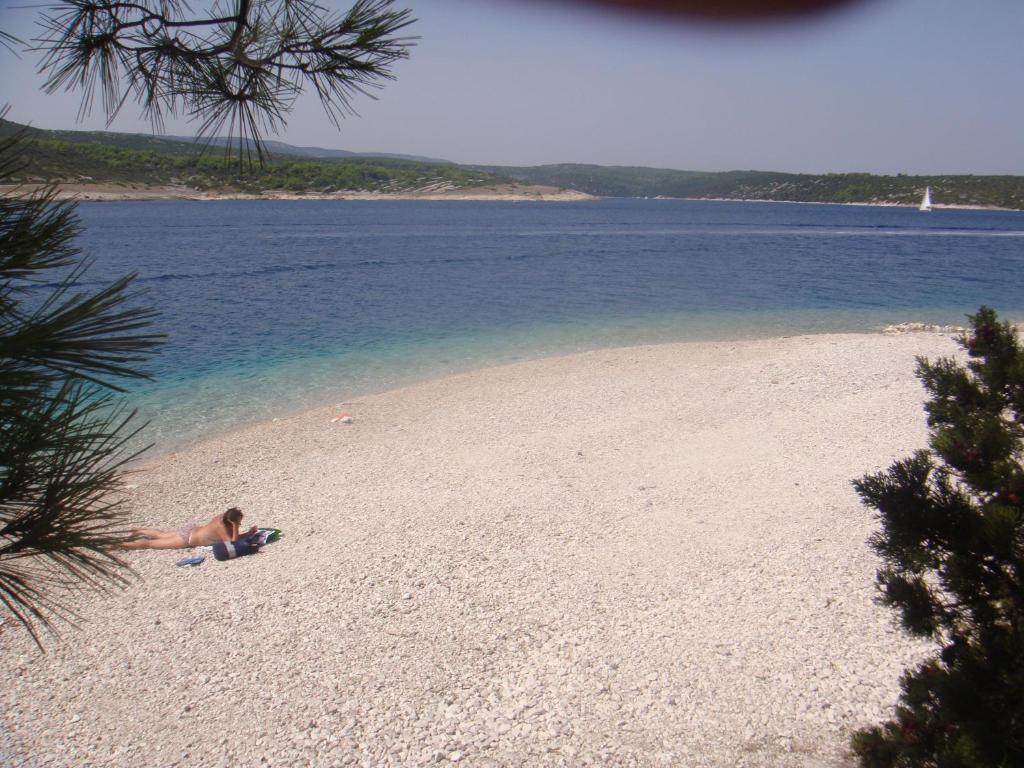 a person laying on a beach next to the water at Apartment Antica in Povlja