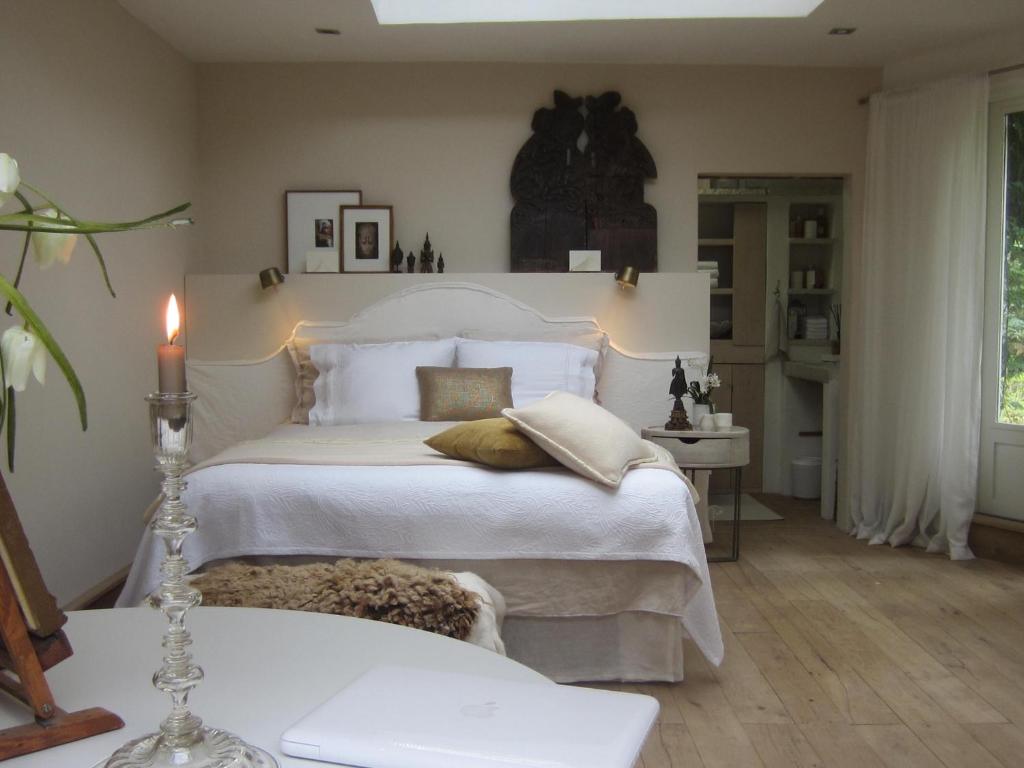 a bedroom with a white bed with a candle on it at La chambre blanche in Heerlen