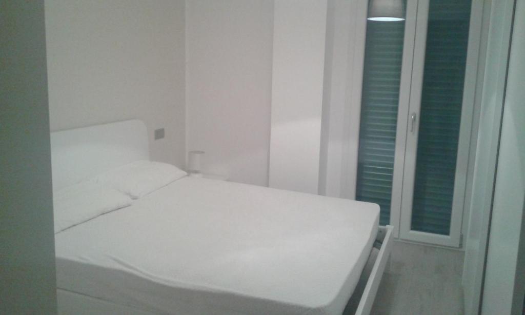 ein weißes Bett in einem weißen Zimmer mit Fenster in der Unterkunft straccia 2 in Cupra Marittima