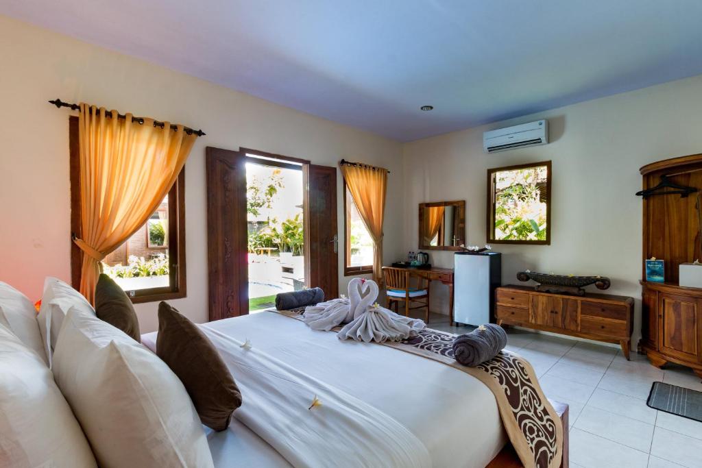 a large bedroom with a large white bed and windows at Arton Resort & Beach Club in Pulukan