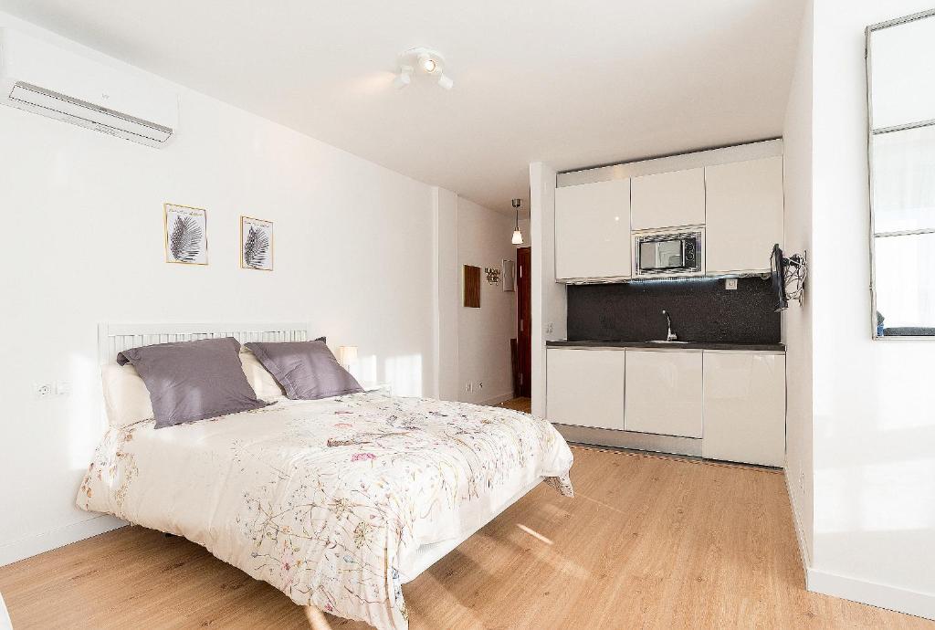 a white bedroom with a bed and a kitchen at Estudio Playa Candado in Málaga