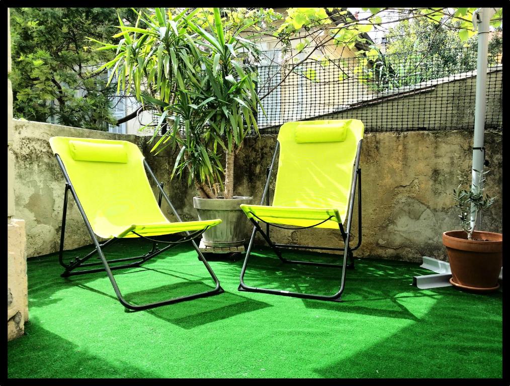 two yellow chairs on a patio with green grass at Proche promenade des anglais et de la mer in Nice