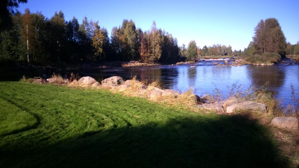 a view of a river with rocks and trees at meijeriranta majoitus in Ylistaro