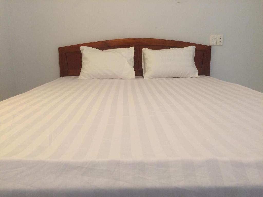a bed with white sheets and two pillows at Y Bon in Phan Thiet