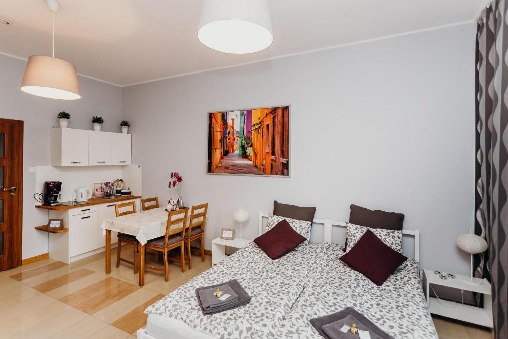 ヴロツワフにあるGrey Apartments IIのベッド、テーブル、キッチンが備わる客室です。