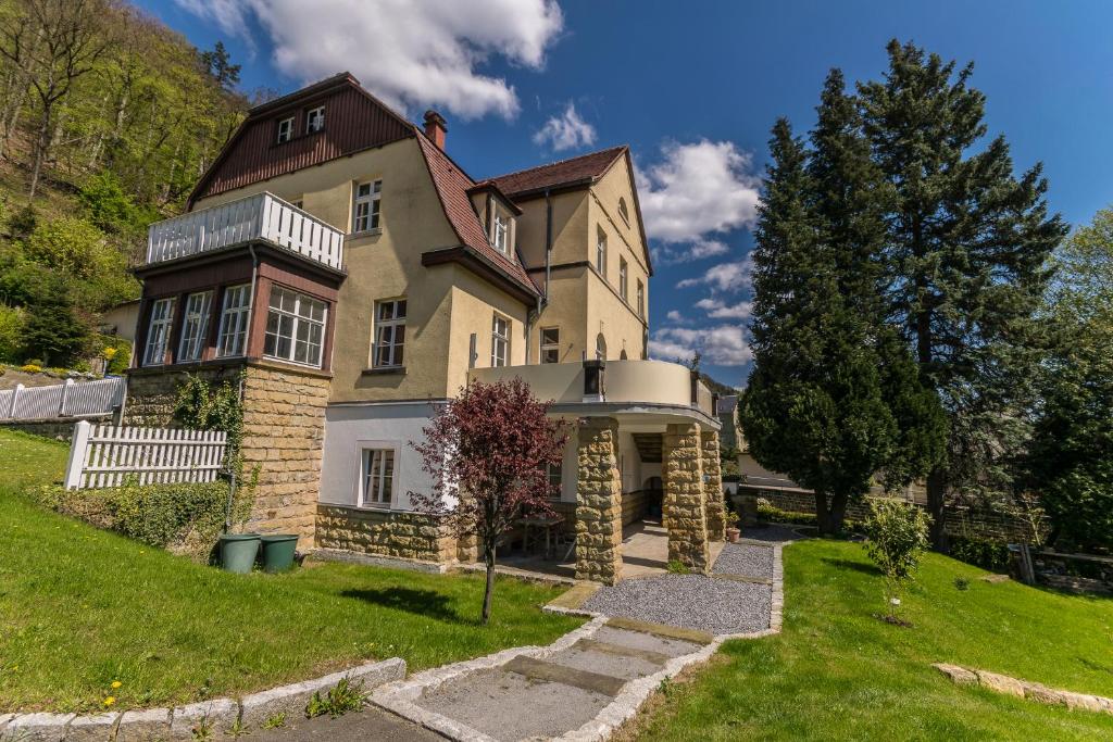 ein großes Haus auf einem Hügel mit einem grünen Hof in der Unterkunft Ferienwohnungen Endler in Bad Schandau