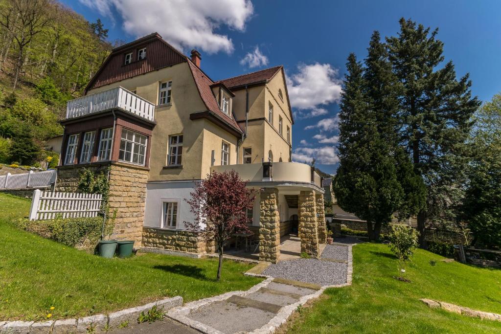 een groot huis op een heuvel met een groene tuin bij Ferienwohnungen Endler in Bad Schandau