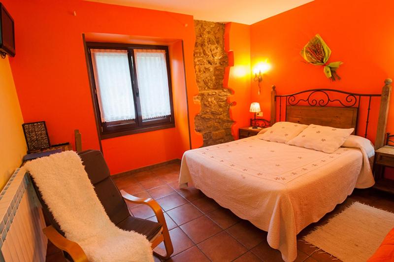 1 dormitorio con paredes de color naranja, 1 cama y 1 silla en Zubeltzu Torre, en Zumaia