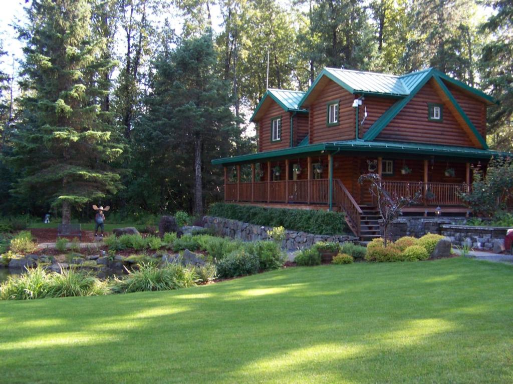 une grande maison en bois avec un jardin en face de celle-ci dans l'établissement Box Canyon Cabins, à Seward