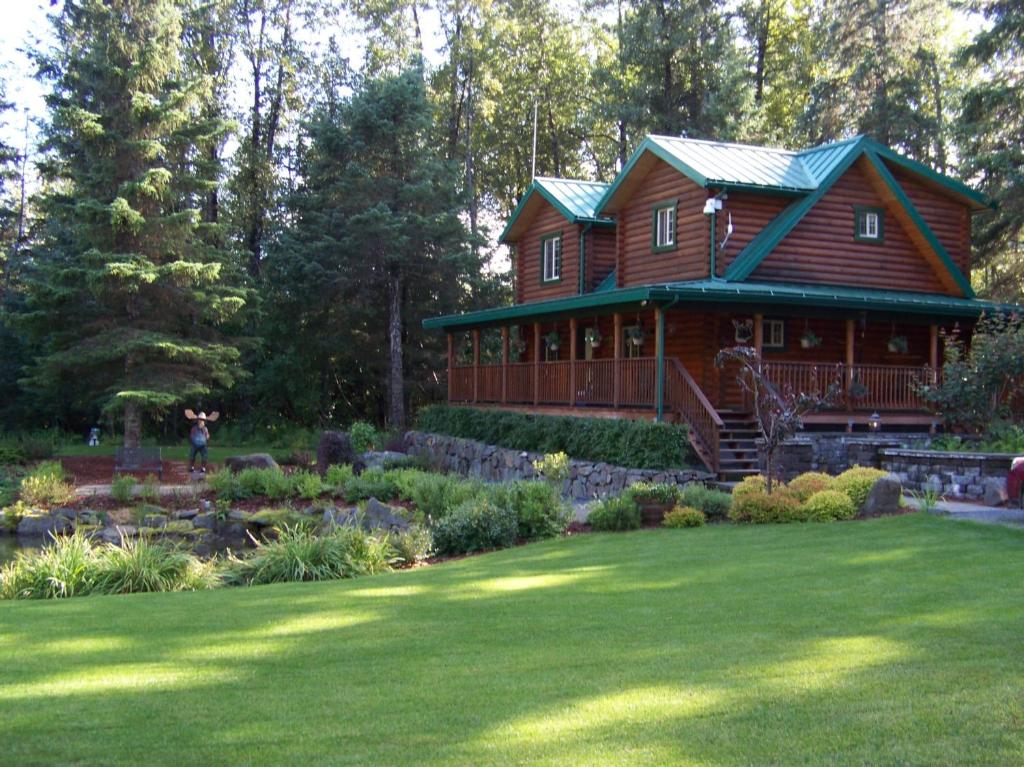 a large wooden house with a garden in front of it at Box Canyon Cabins in Seward