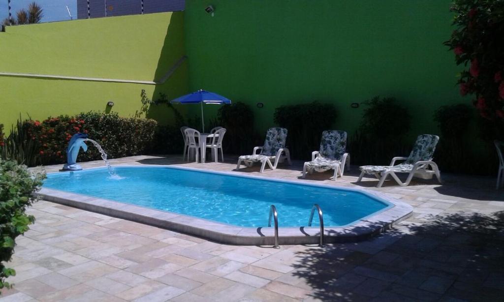 a swimming pool with a fountain and chairs and a green wall at Pousada Jesmar in Praia do Frances