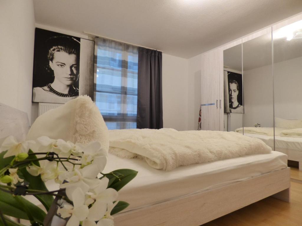 a white bedroom with a bed and a mirror at Domino Apartment in Baden-Baden