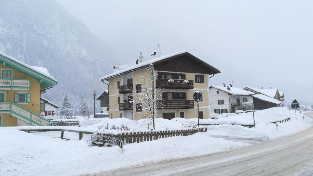 a building on a street with snow on the ground at CasaMau Trilo in Campitello di Fassa
