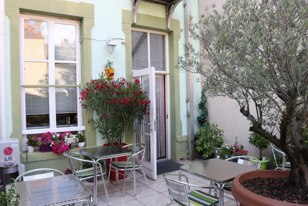 een patio met tafels, stoelen en bloemen bij Logis-Hôtel des Oliviers in Thionville