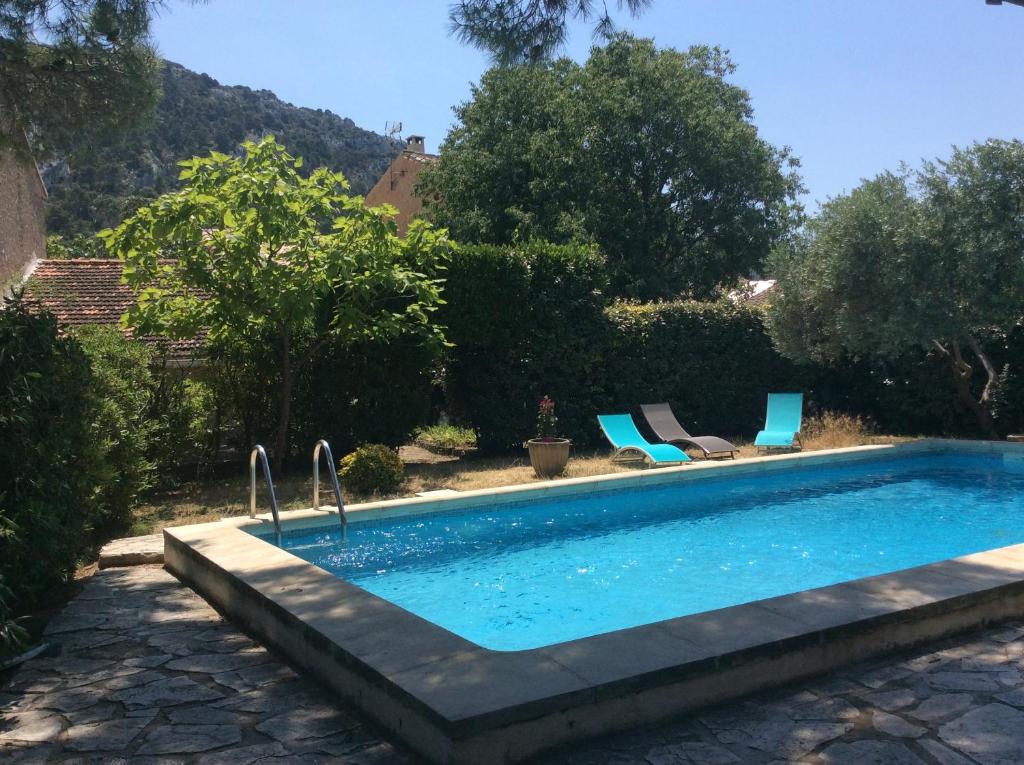 una piscina con 2 sillas azules al lado en Maison Daumas Billard Français et Piscine, en Robion en Luberon