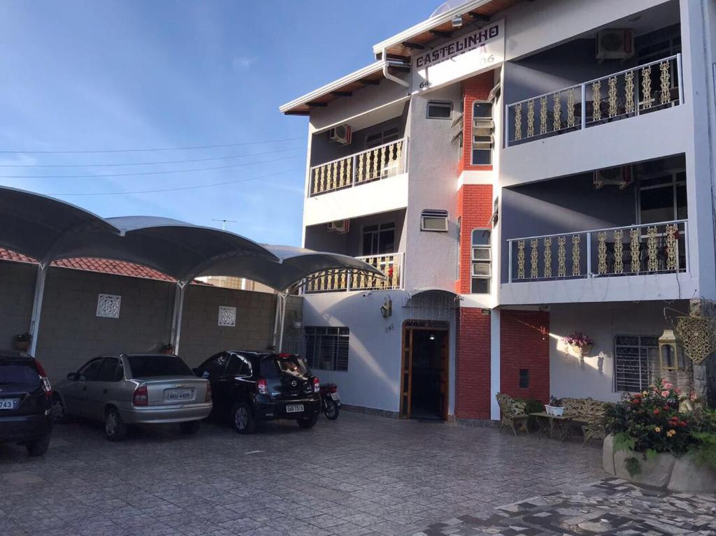 a building with cars parked in a parking lot at Pousada Castelinho in Caldas Novas