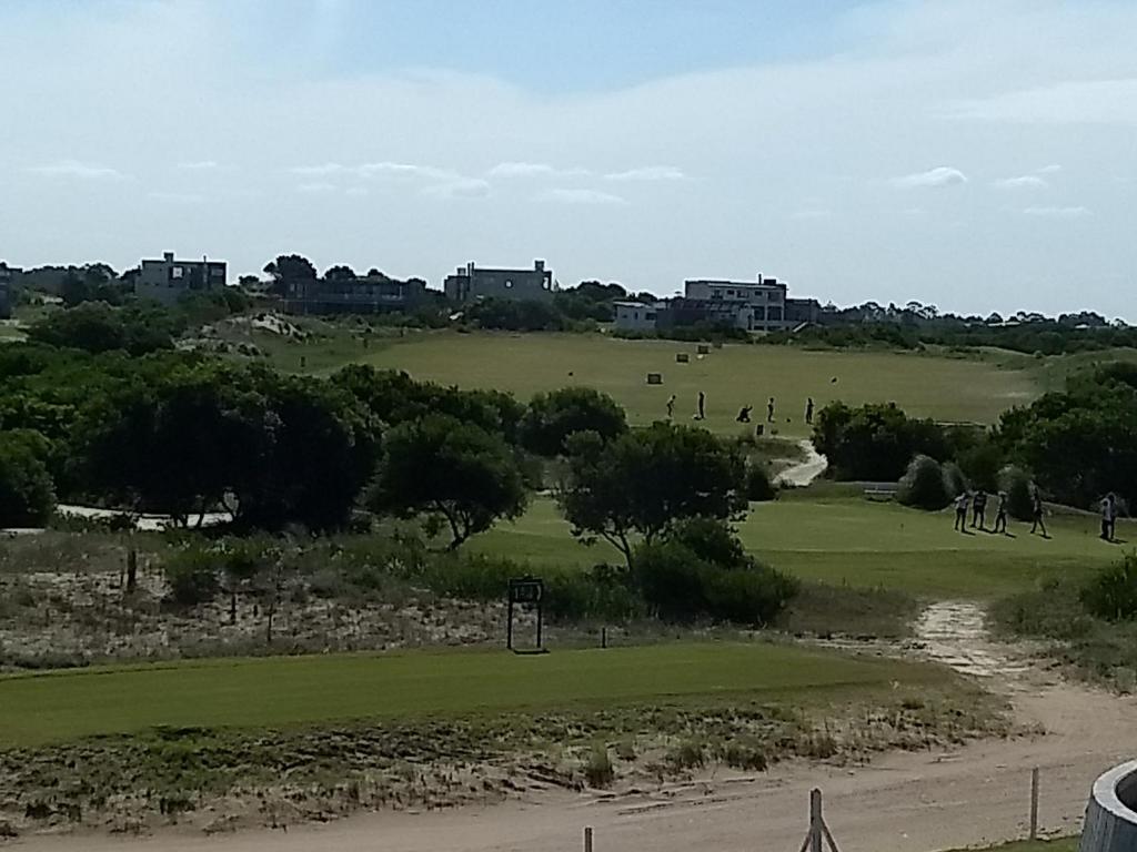 una vista de un campo de golf con gente en una colina en Costa Esmeralda Departamento para 6 Personas sobre el Golf en Pinamar