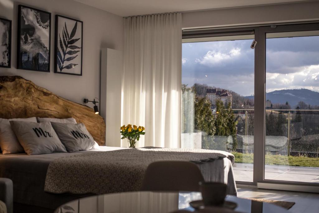 a bedroom with a bed and a large window at ApartWisła in Wisła
